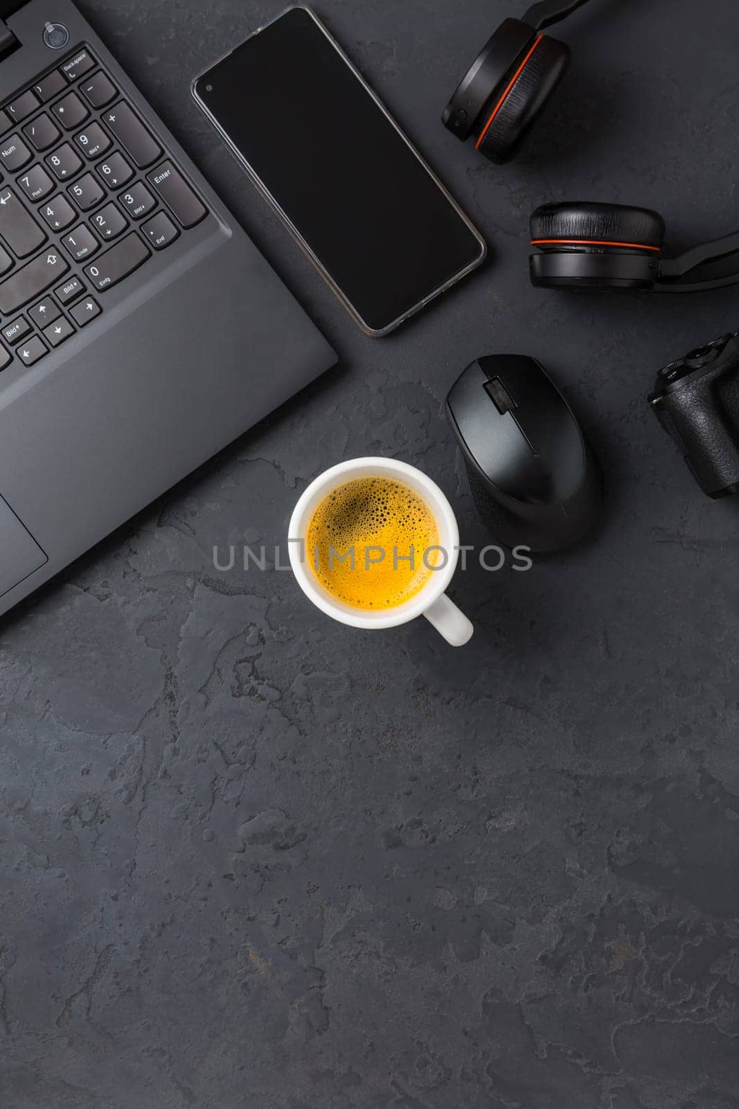 Working place and office desk with coffee, laptop, headset and smarthpone. Flatlay in black tone.