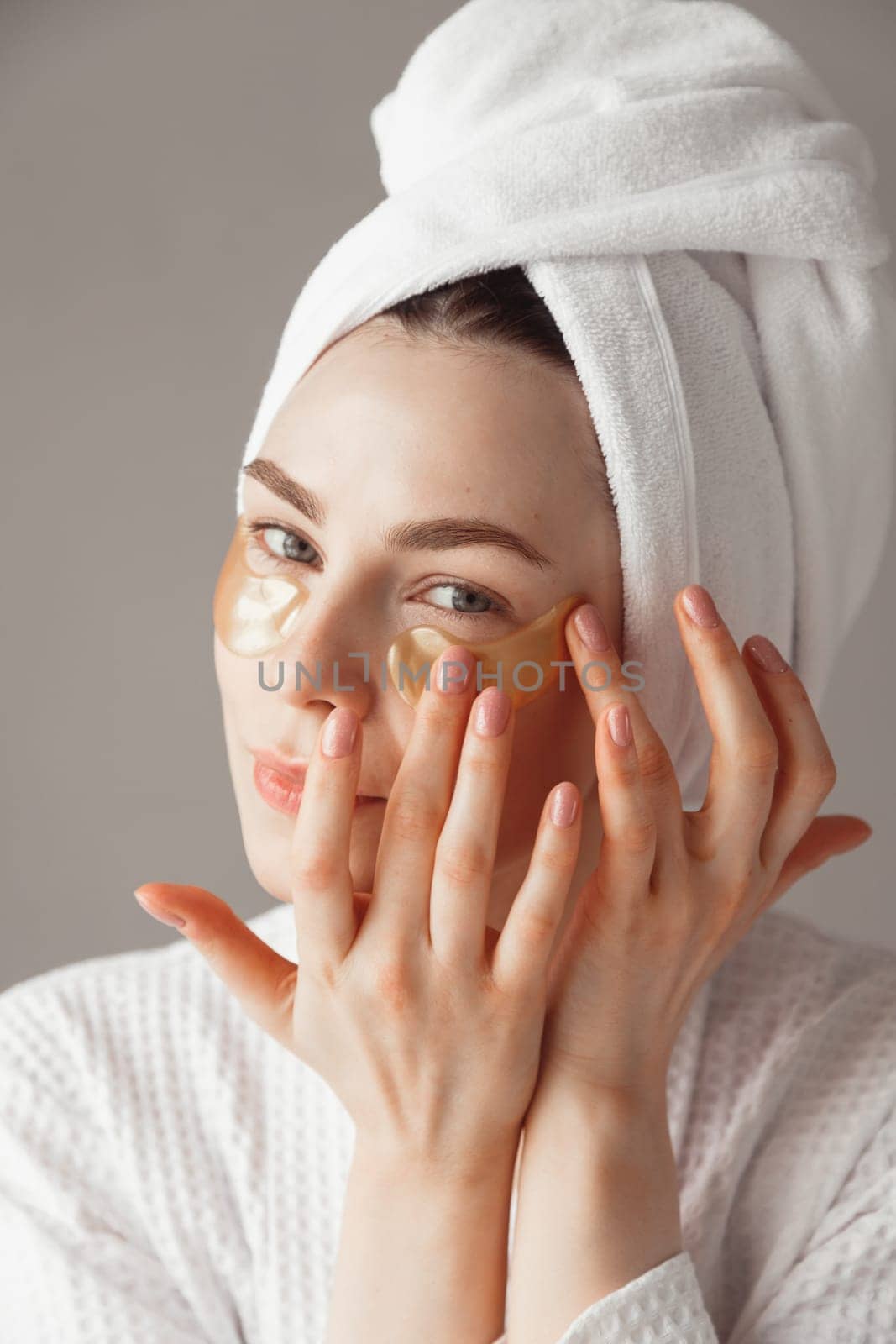 Pretty european girl applying golden collagen patches under her eyes. Woman facial treatment. Cosmetology, beauty and spa