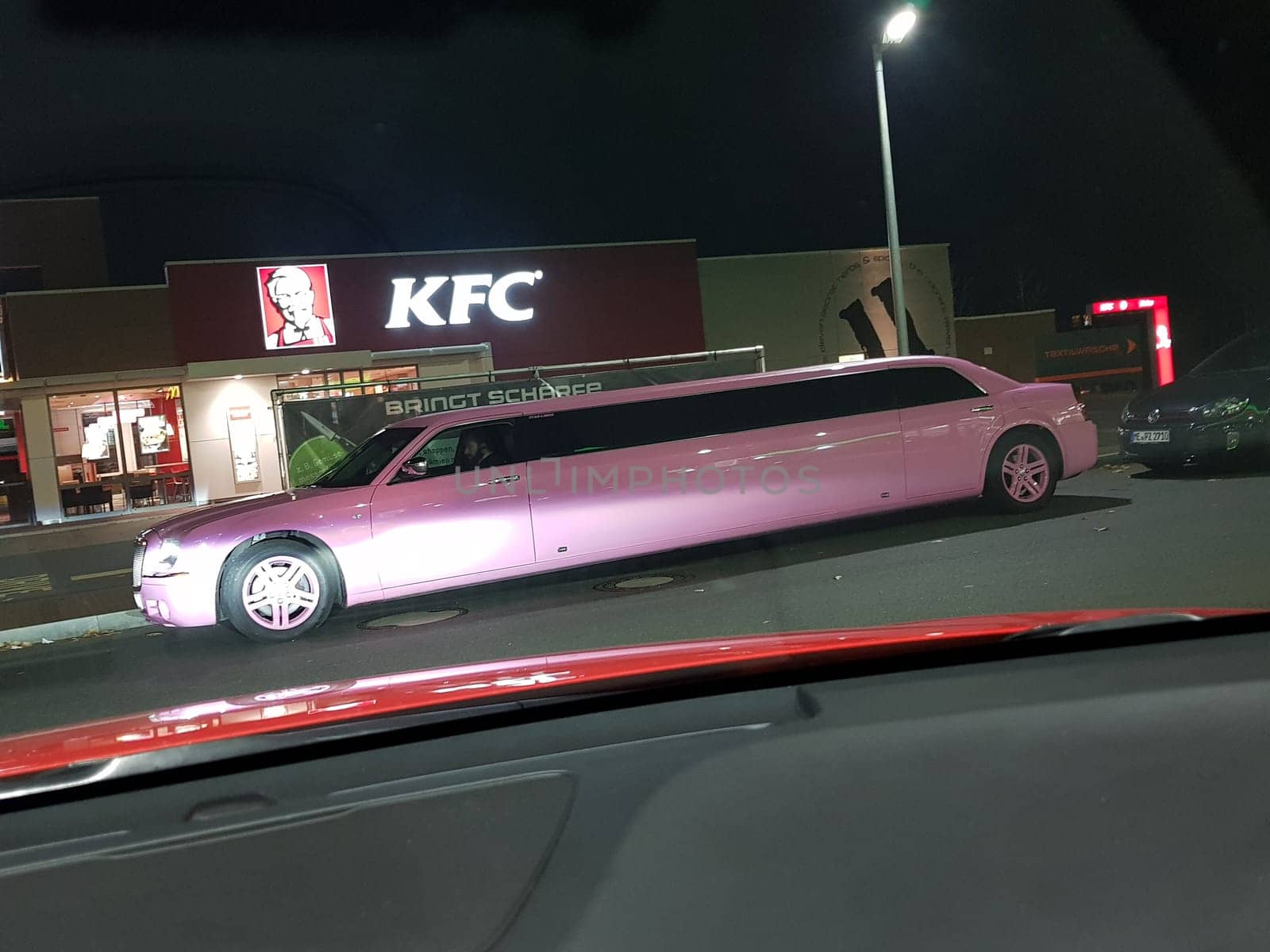 VELBERT, NRW, GERMANY - NOVEMBER 17, 2018:.A pink stretch limousine waits for the arrival of passengers in front of a Kentucky Fried Chicken restaurant in Velbert. Luxury vehicles and stretch limousines