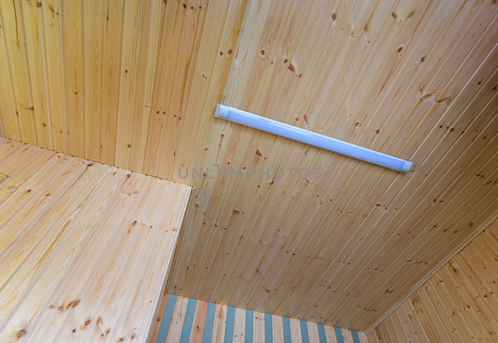 View of a ceiling made of wood clapboard with fixed length LED daylight lamp