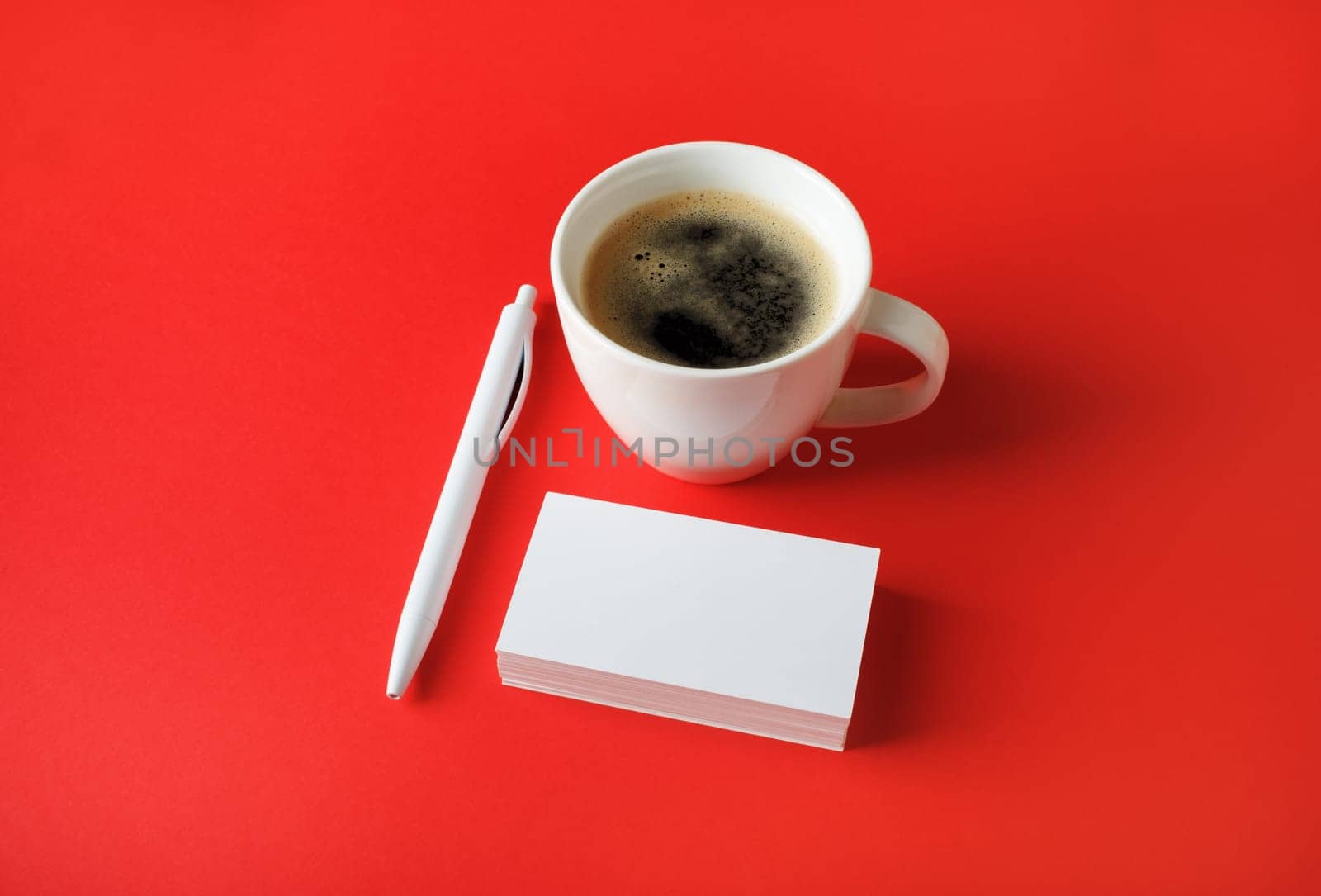Corporate identity template. Blank business cards, coffee cup and pen on red paper background.