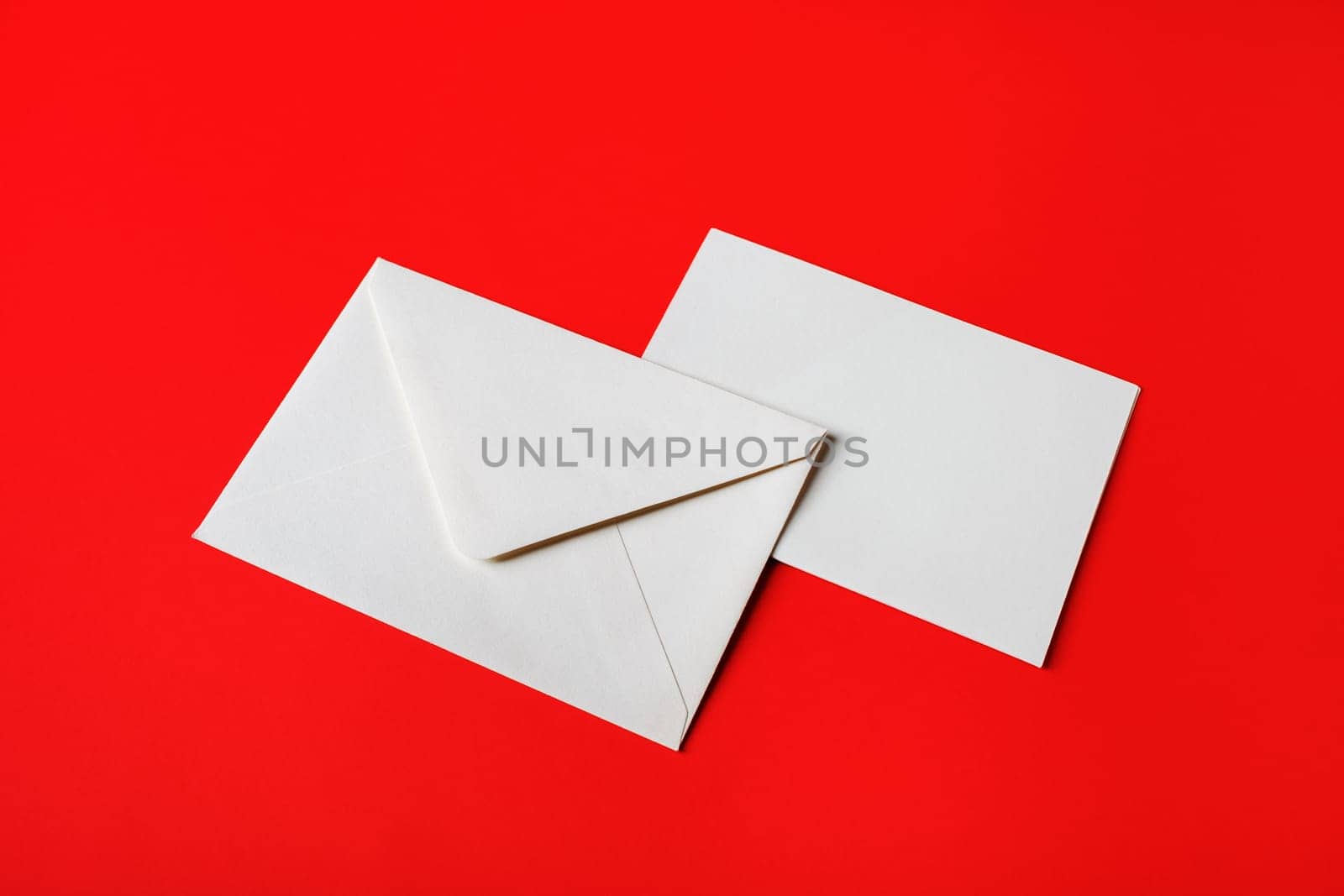 Blank paper envelopes on red paper background. Back and front. Mockup for placing your design.
