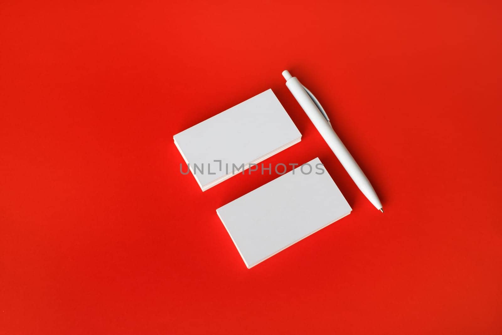 Photo of blank white business cards and pen on red paper background. Copy space for text.