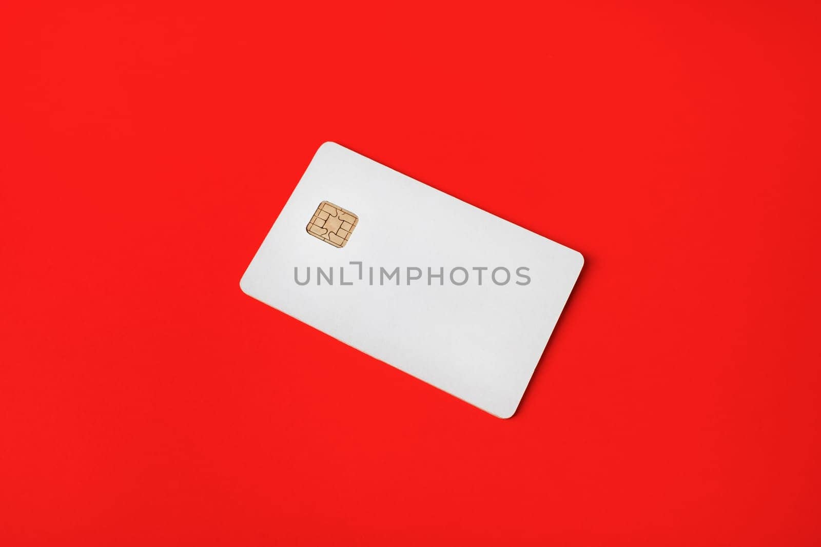 Photo of blank credit card on red paper background. White bank card.