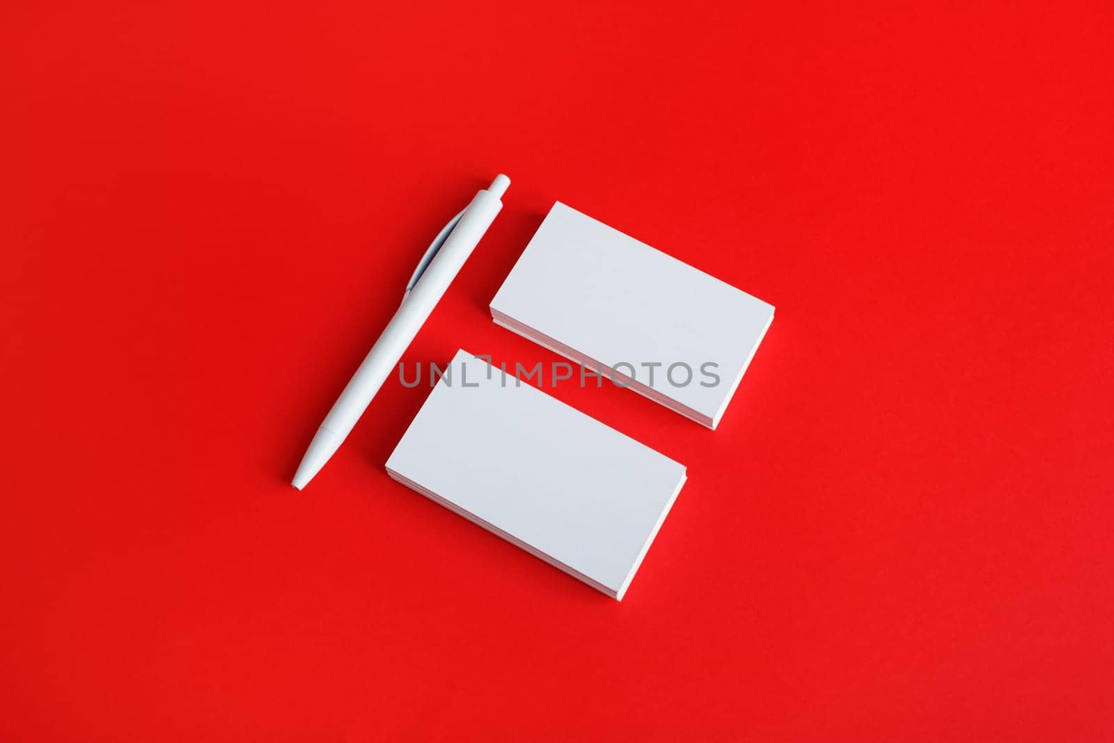 Branding stationery mockup on red paper background. Blank objects for placing your design. Blank business cards and pen.
