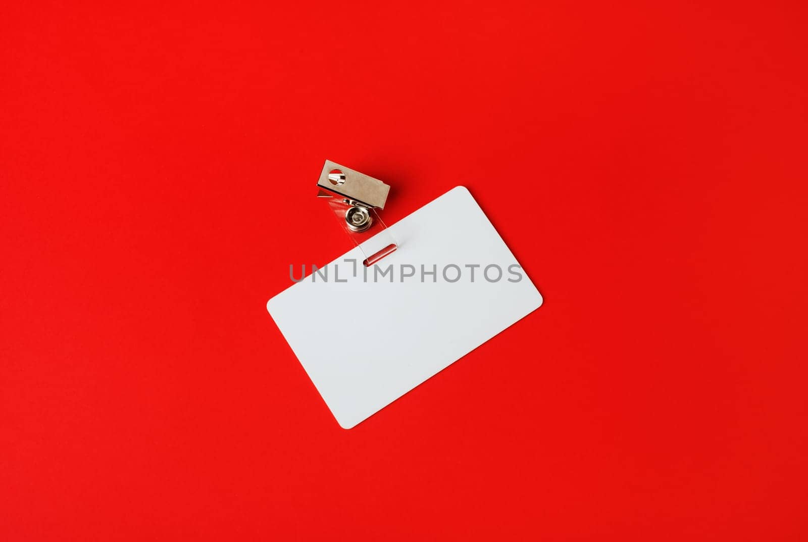 White ID card. Blank security badge on red paper background. Copy space for text.