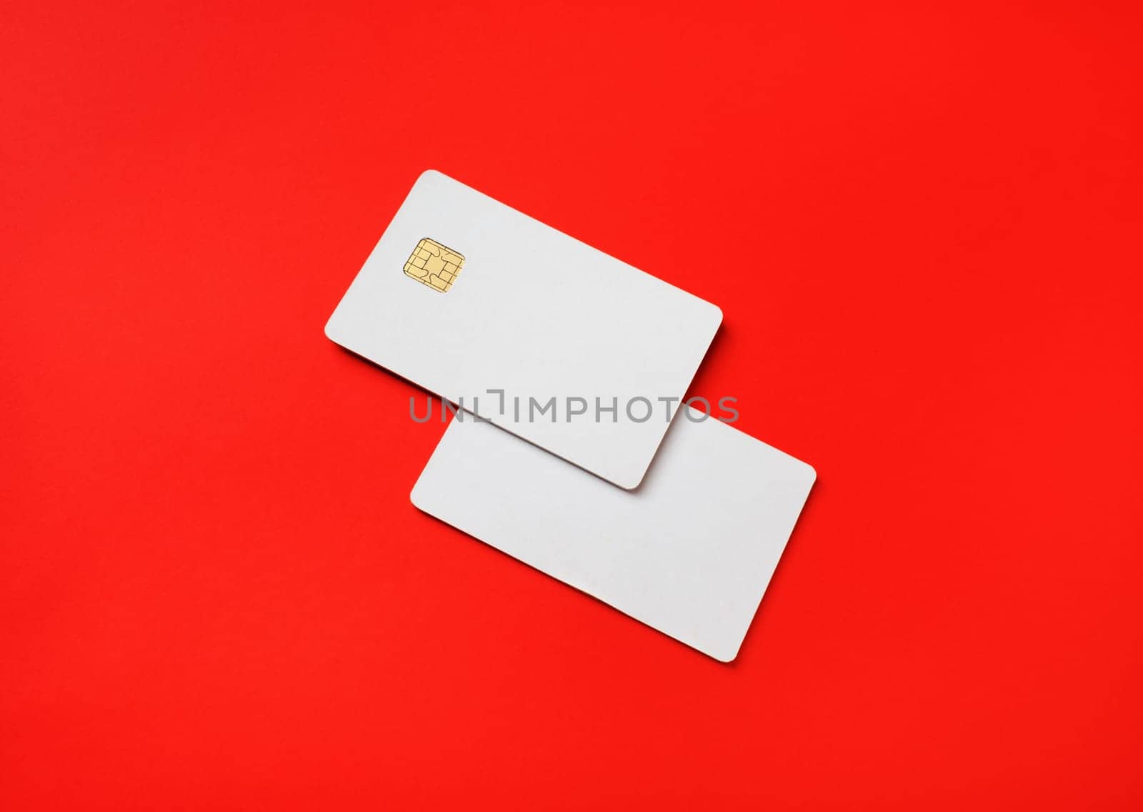 Photo of two blank credit cards on red paper background. White bank cards.