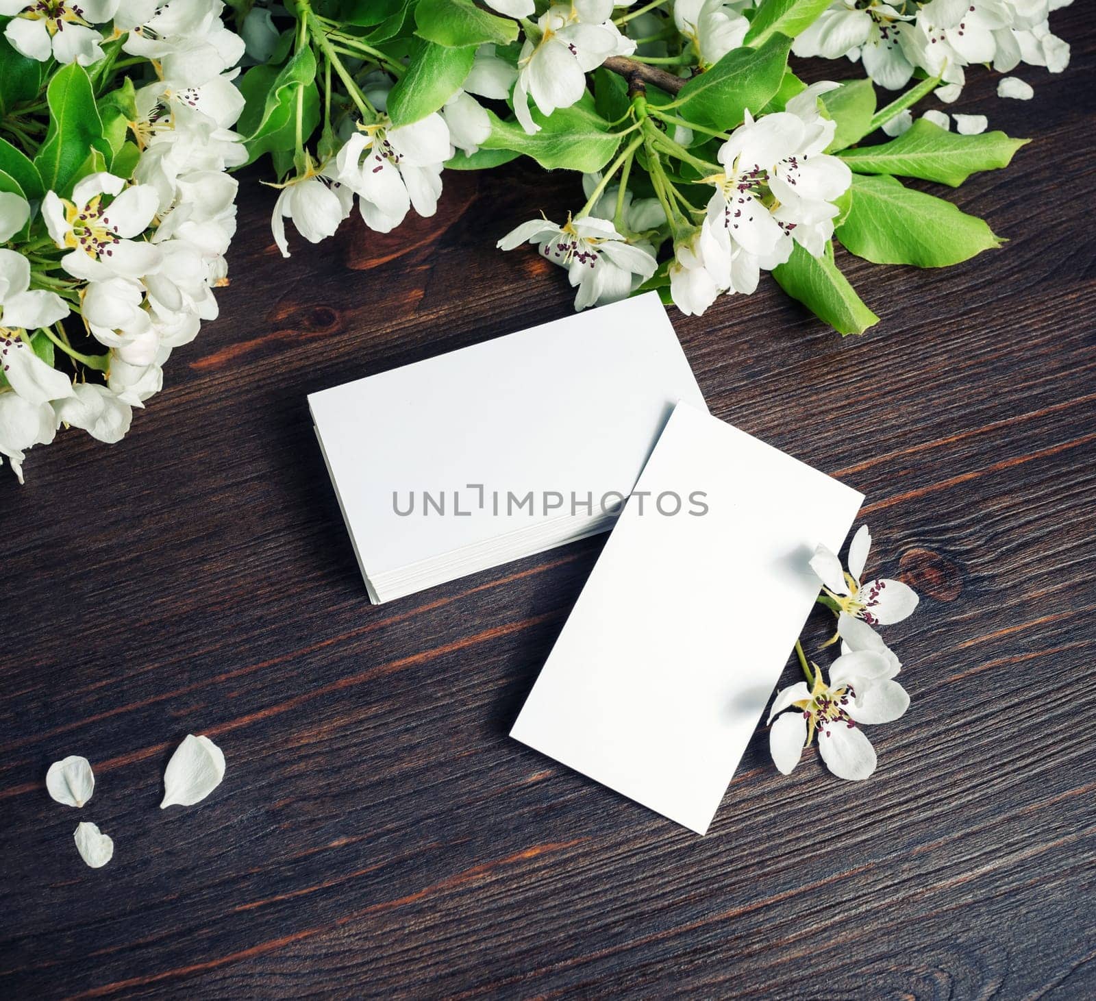 Blank business cards and flowers on wood table background. Template for ID.