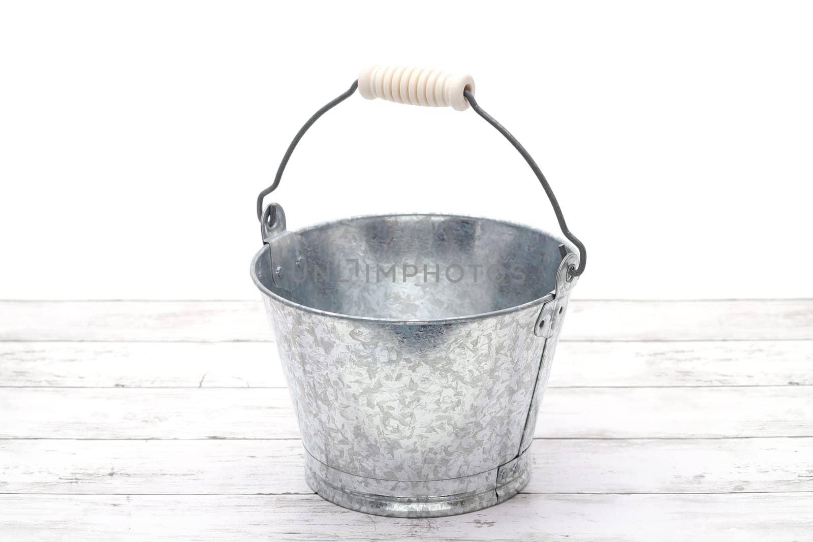 Empty metal bucket on white grunge wooden table