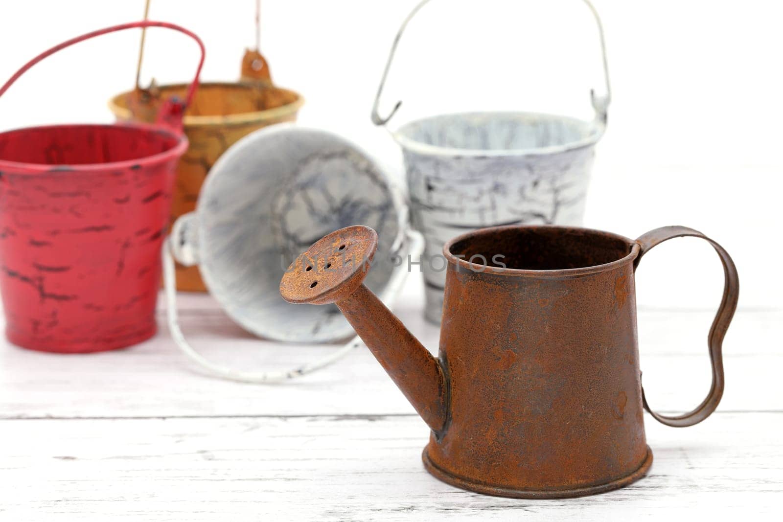 rusted old miniature watering can with bucket on wooden white table