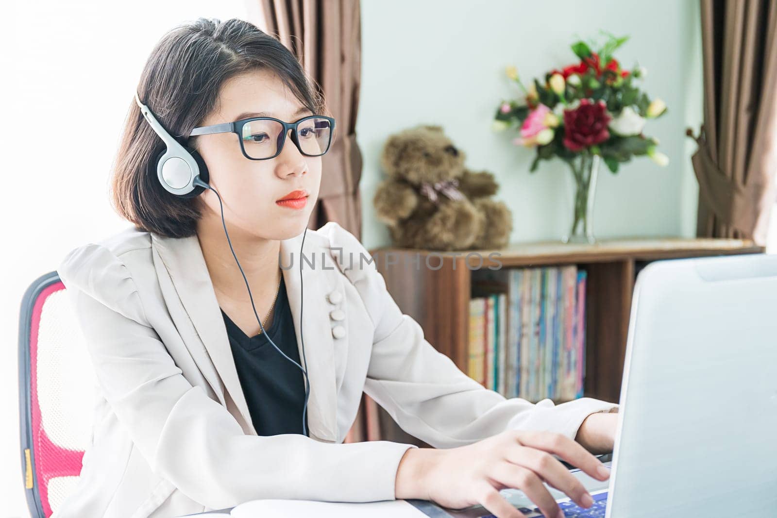 Teenage girl short hair in smart casual wear working on laptop while sit near window in home office