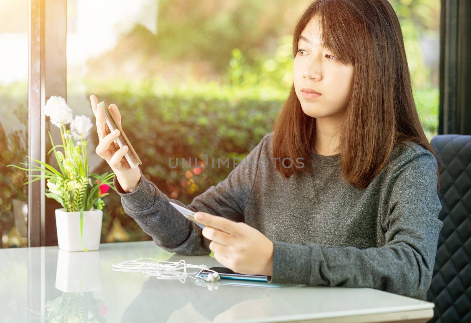 Young woman sitting sholding passport and credit card in home office
