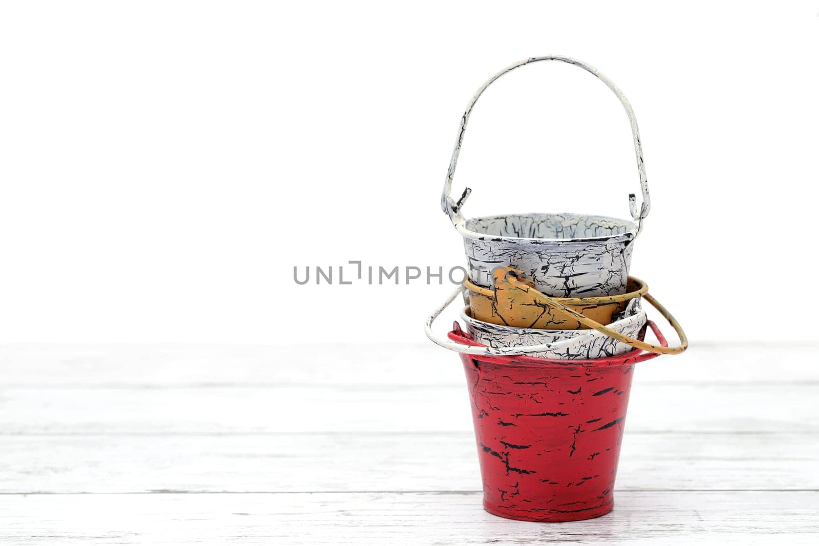 Empty miniature metal bucket on white wooden table