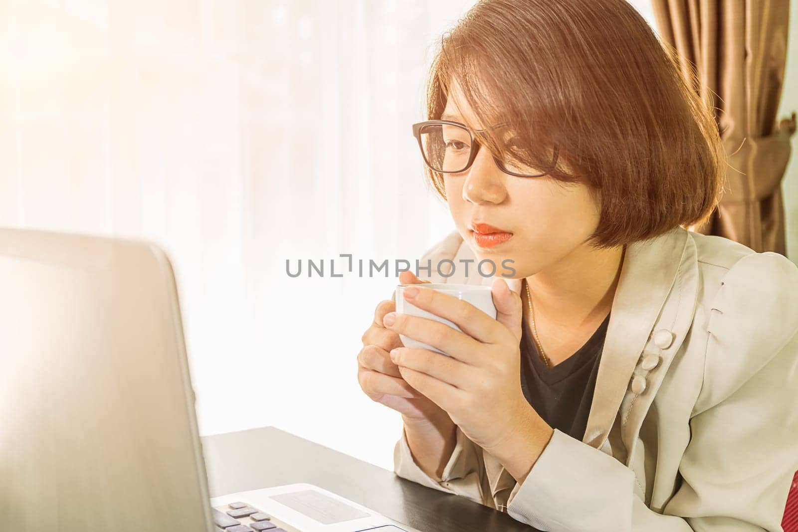Woman teenage short hair in smart casual wear working on laptop while sit near window in home office