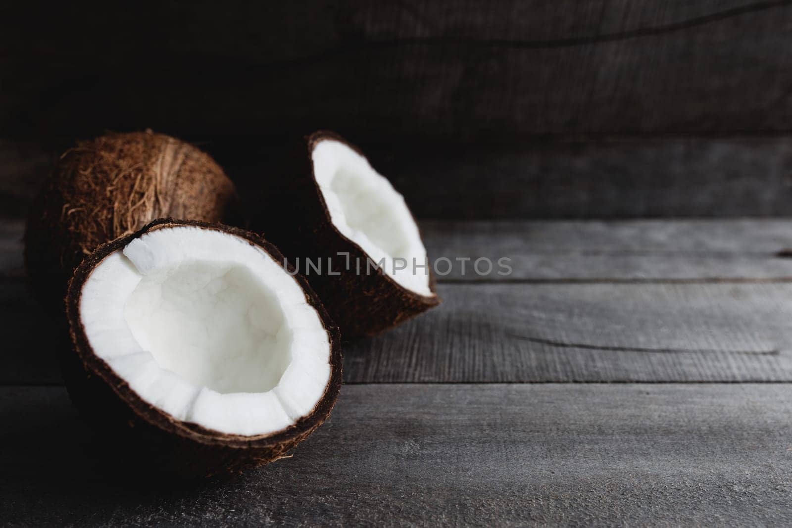 Broken coconuts on gray wooden background. White coconut pulp. High quality photo