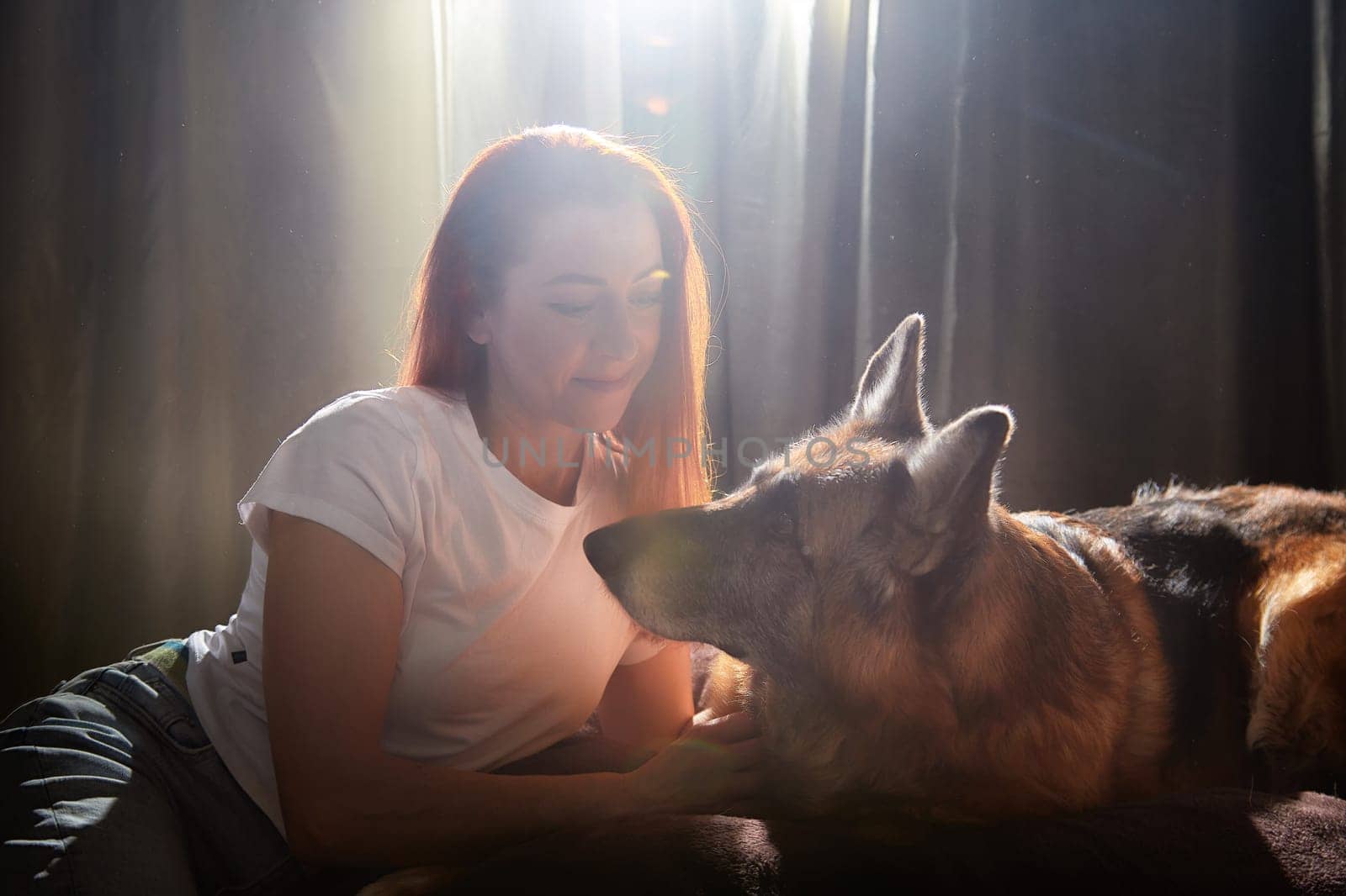 A woman lovingly interacts with her German Shepherd dog in a warm and inviting indoor space.