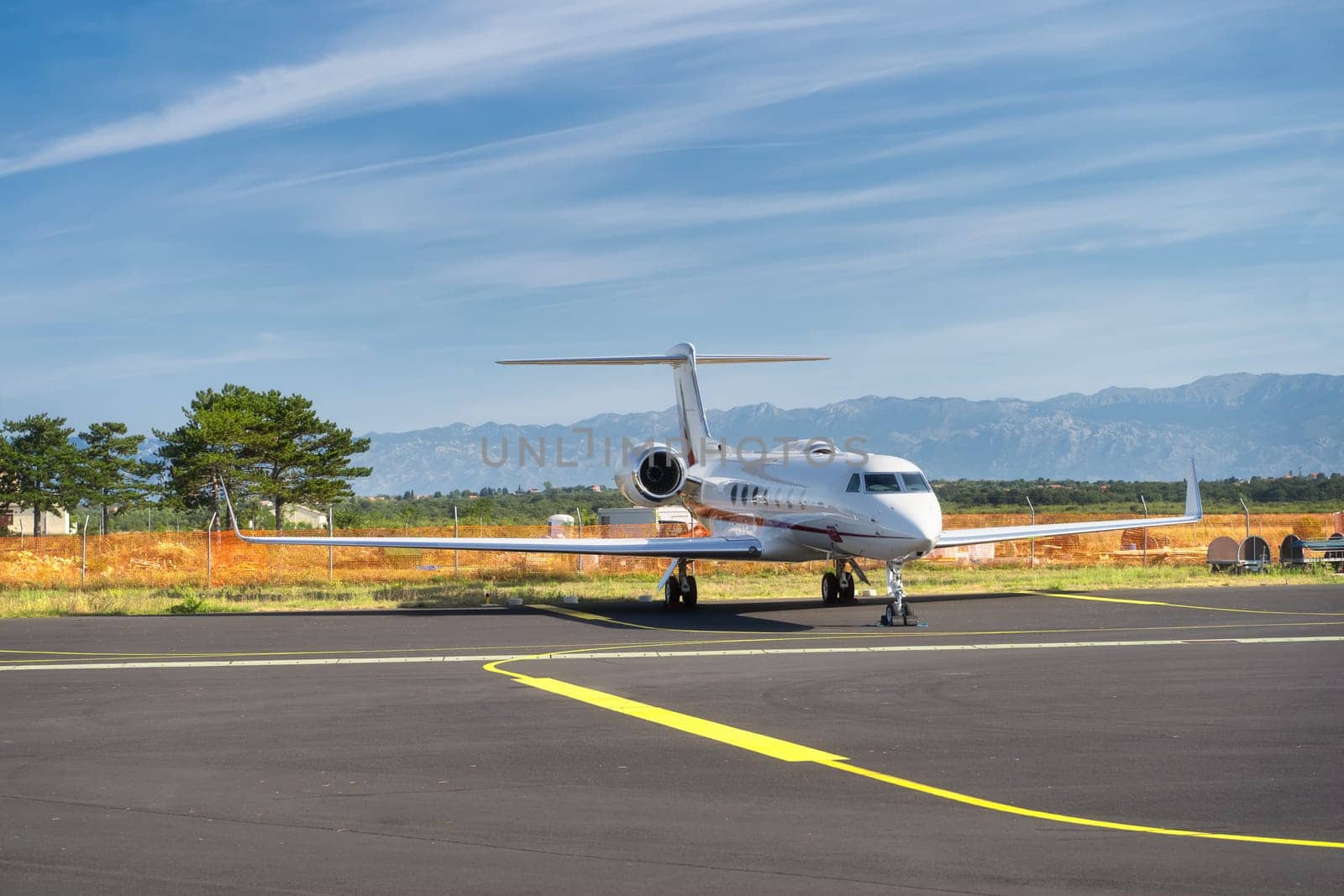 Small airplane parked on airport. Use of private jets to avoid coronavirus risk and restrictions. Dinaric Alps mountains in background, Zadar, Croatia