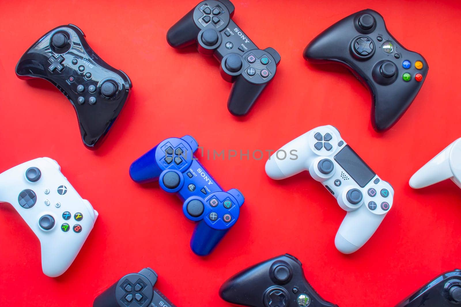 Calgary, Alberta, Canada. Feb 13, 2021. Several video game control remote from the most popular game consoles on a red background