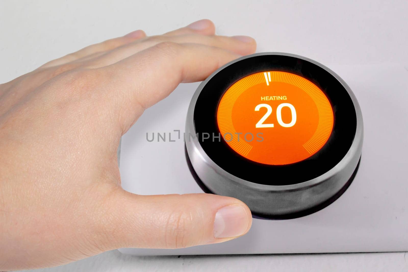 A person adjusting the temperature on a smart thermostat during winter
