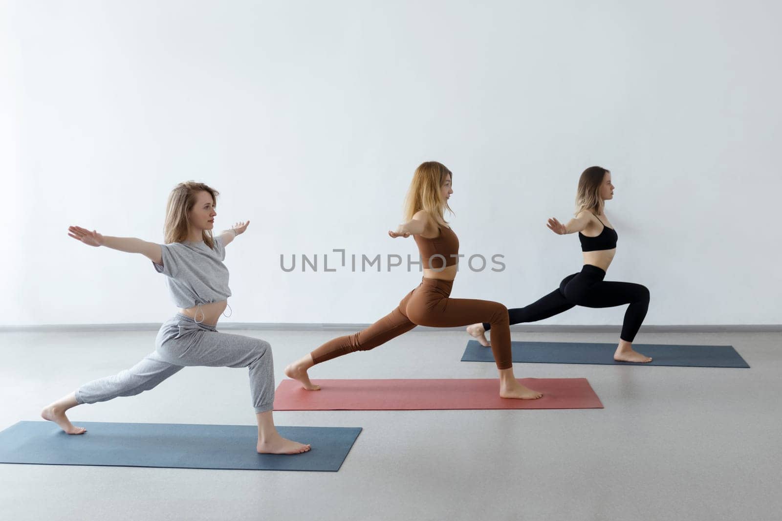Young girls in a warrior pose at a group yoga class. Healthy lifestyle and female beauty.