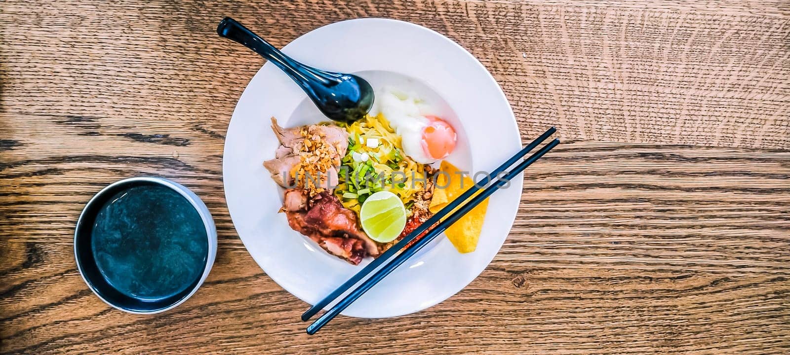 Miso Soup with Asian noodles with egg in bowl on wooden table background  with chopsticks and spoon