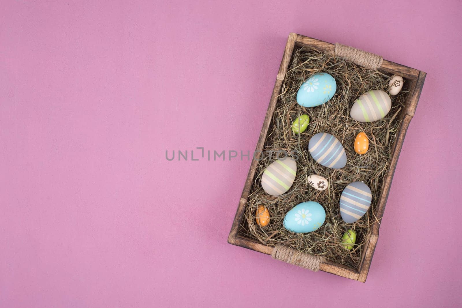 Colored easter eggs in a basket with hay, empty copy space for text