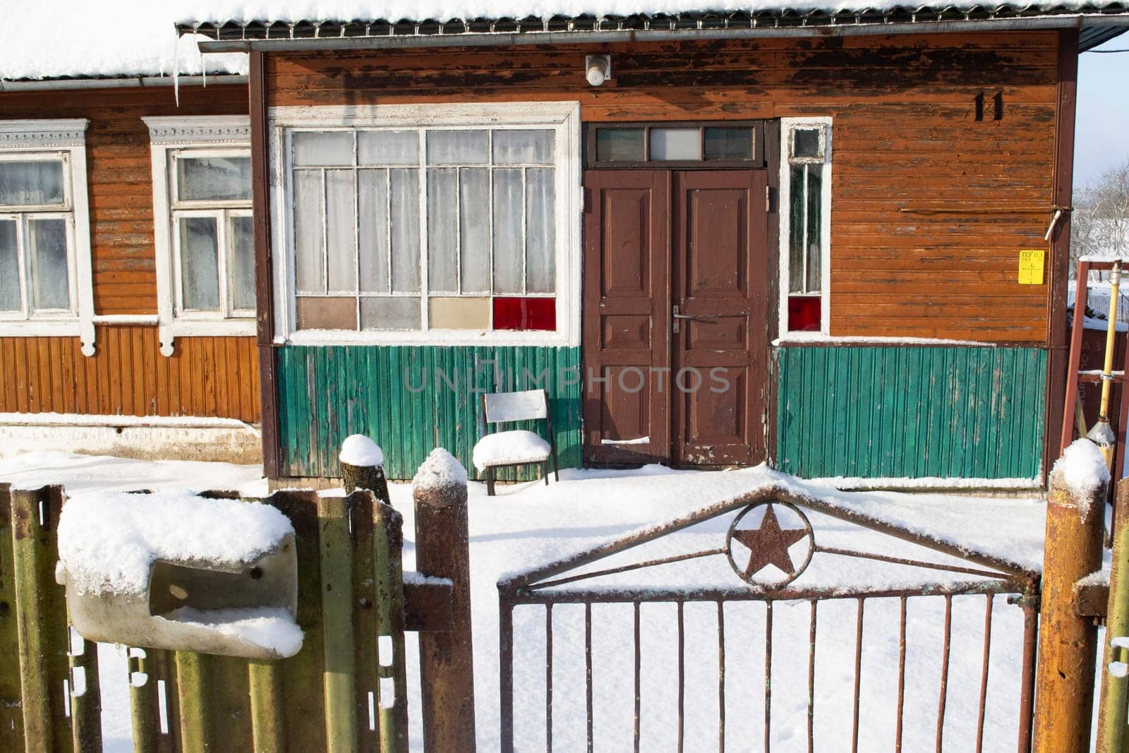 Facade of a traditional belarussian village old wooden house in winter with fence