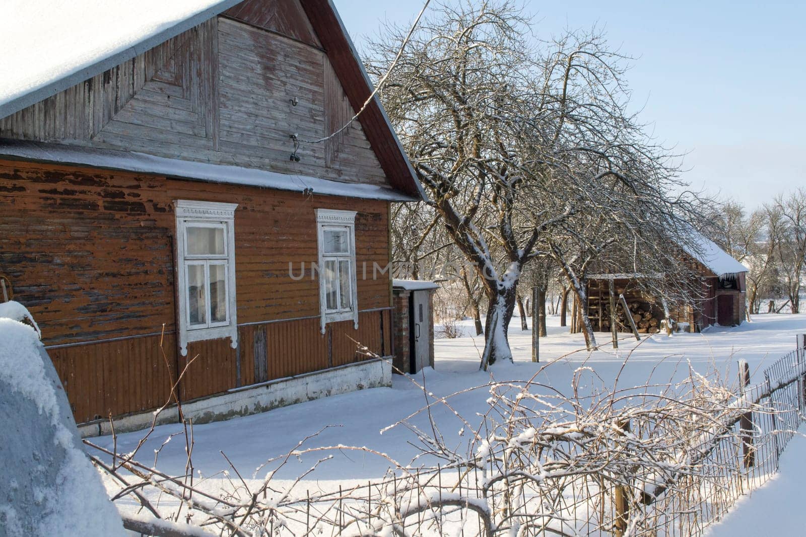 Old wooden house covered with fresh fallen snow. Uninhabited old winter cozy cottage in empty village. Rural snowy landscape