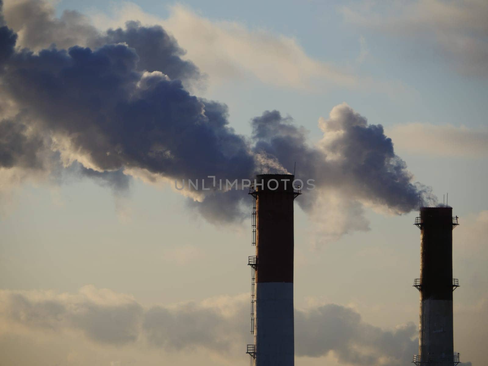 One chimney emits smoke into the blue sky