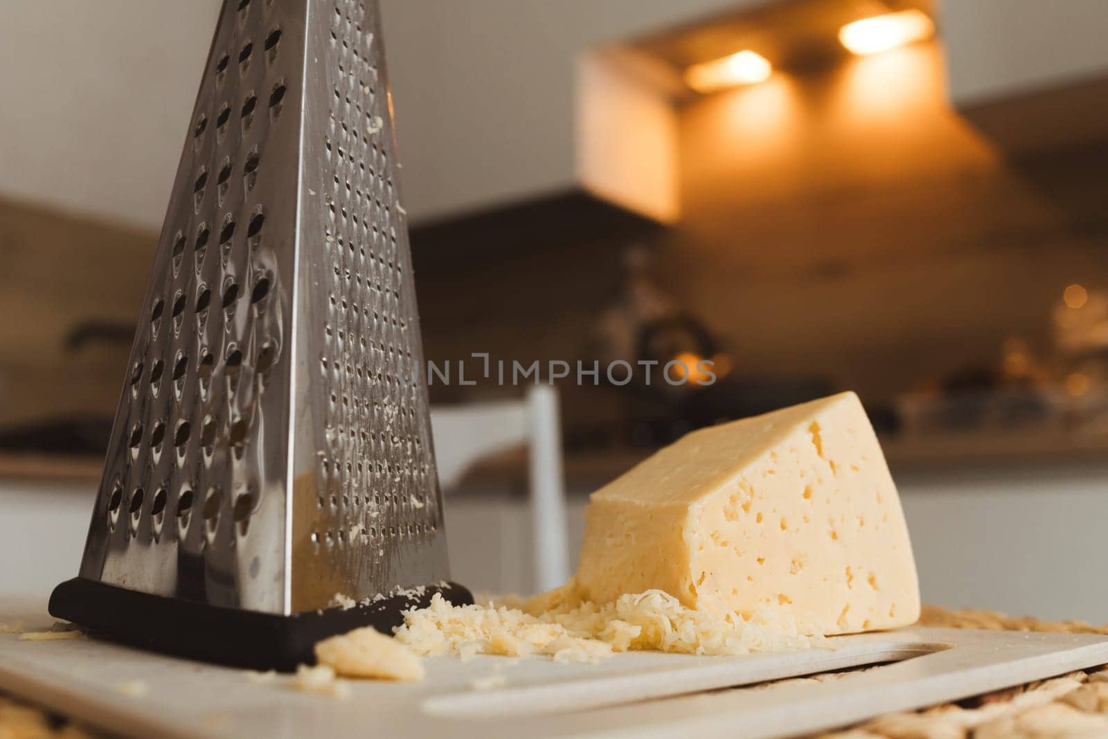 Grater and cheese on kitchen table. Cooking, food and home concept.