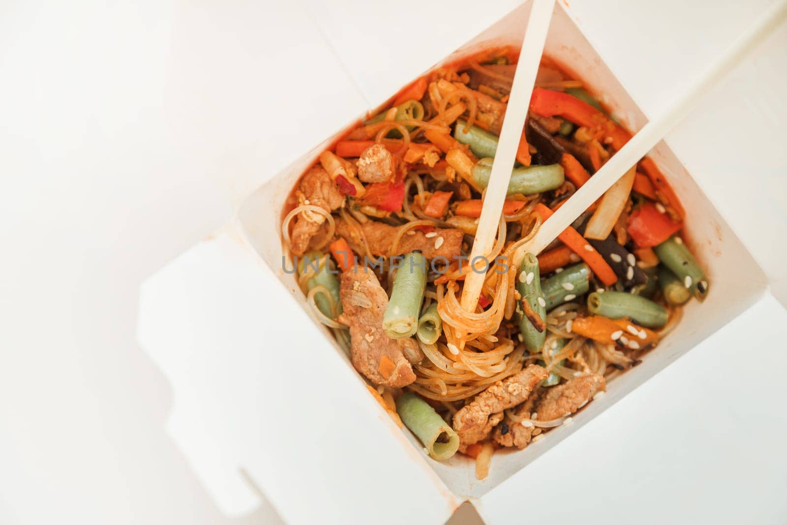 Wok noodles in takeaway box. Wheat noodles with peking duck and vegetables. Traditional chinese cuisine.