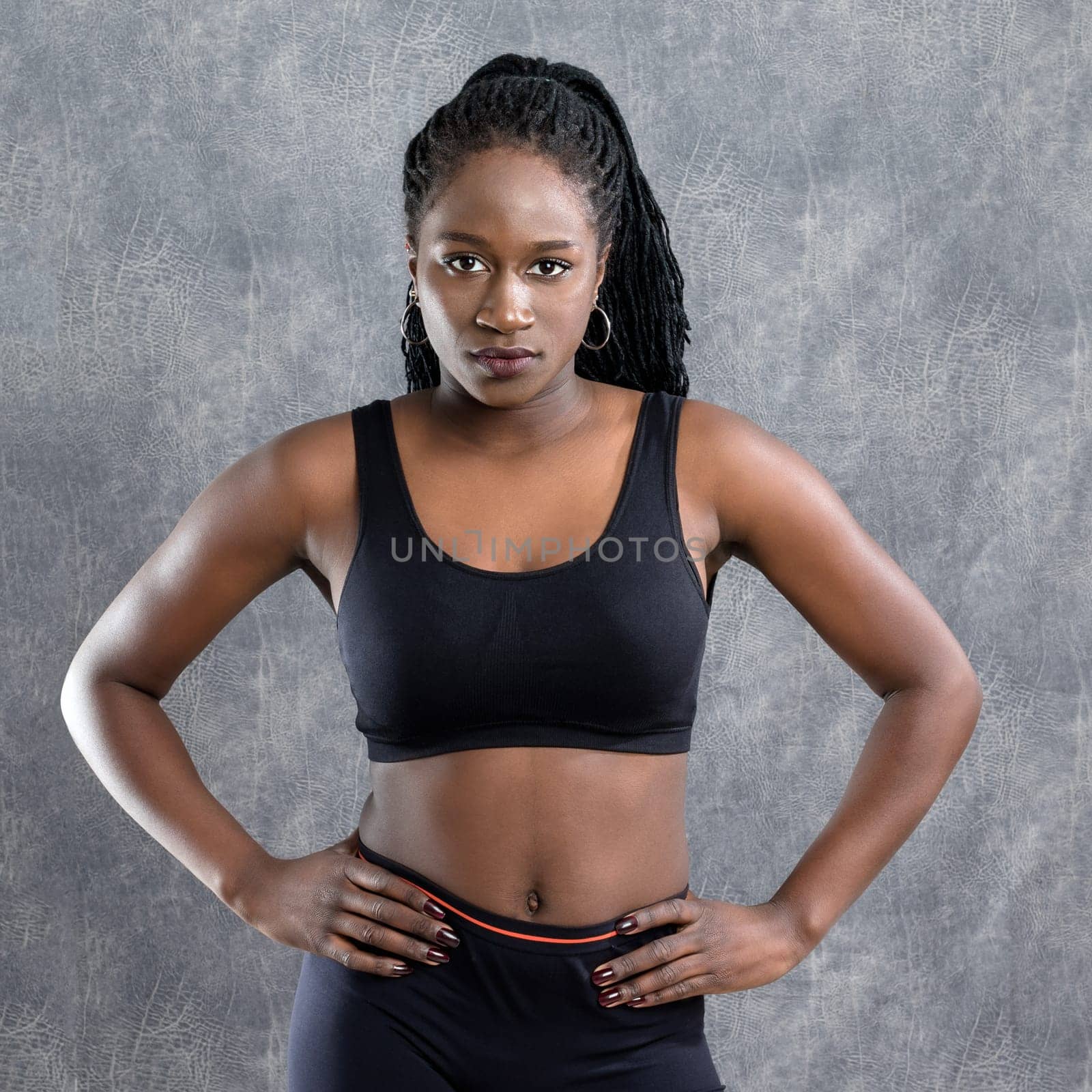 Close up studio portrait of muscular african teen runner in sportswear against grey background.