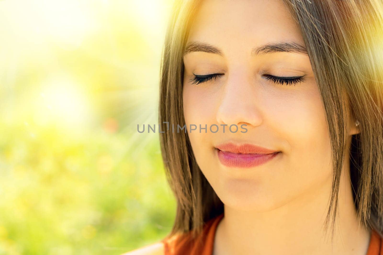 Close up portrait of attractive relaxed young woman meditating outdoors.Girl with eyes closed against bright colorful outdoor background.