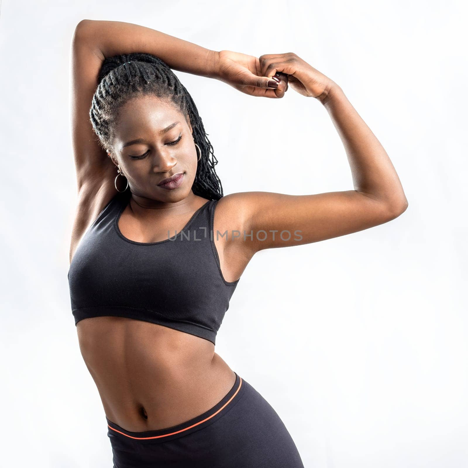 Close up of muscular african teen girl doing stretching exercise.Young woman in sportswear  hips isolated on white background.