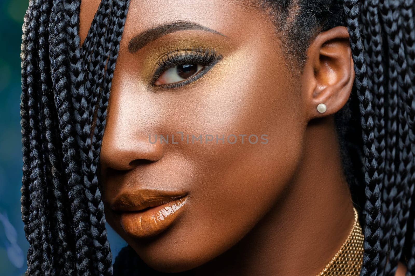 Extreme close up facial beauty portrait of  young charming african girl with braided hairstyle.Studio shot of woman with professional make up looking at camera.