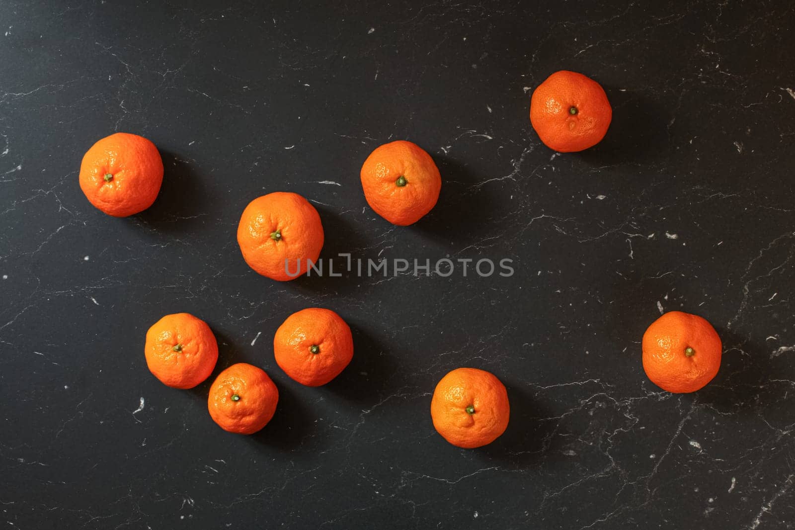 Top down view, mandarines tangerines on black marble board.
