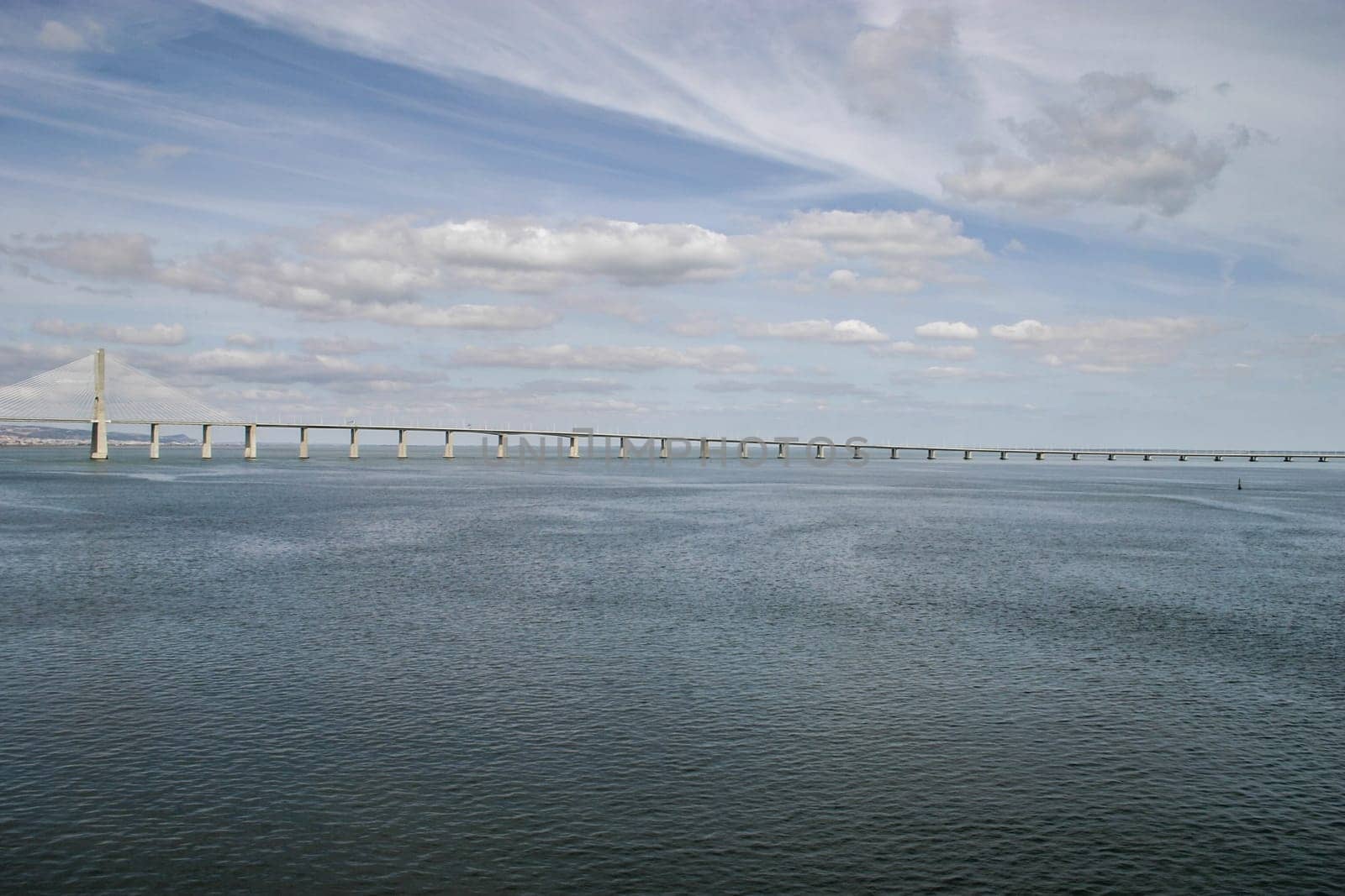 Lisbon, Portugal - September 17, 2006: River Tagus with Vasco da Gama Bridge and dramatic sky in background.
