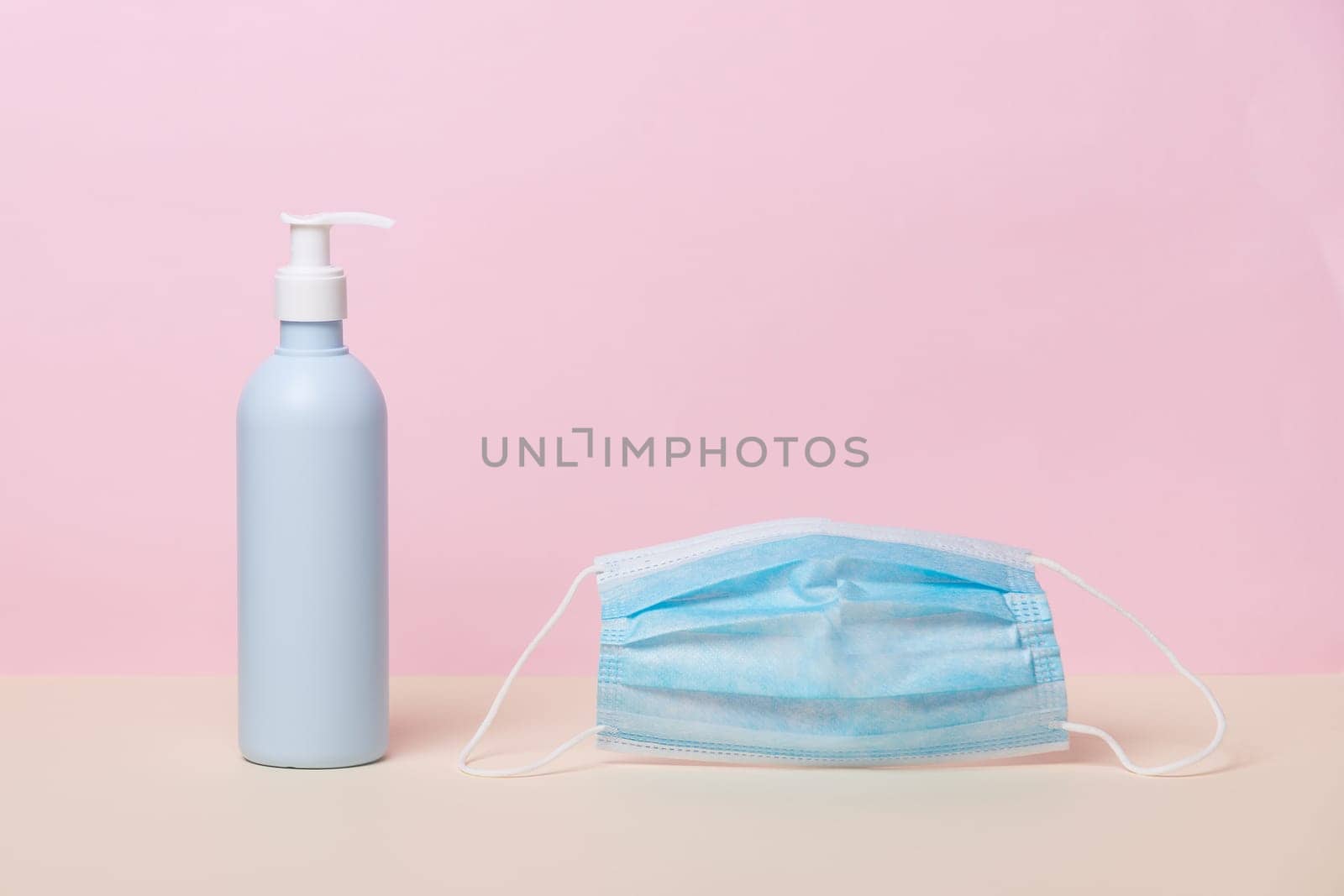 Coronavirus prevention medical surgical mask and sanitizer gel for hands, corona virus (covid-19) protection. Antiseptic, Hygiene and Health concept. Minimalist style on pink background