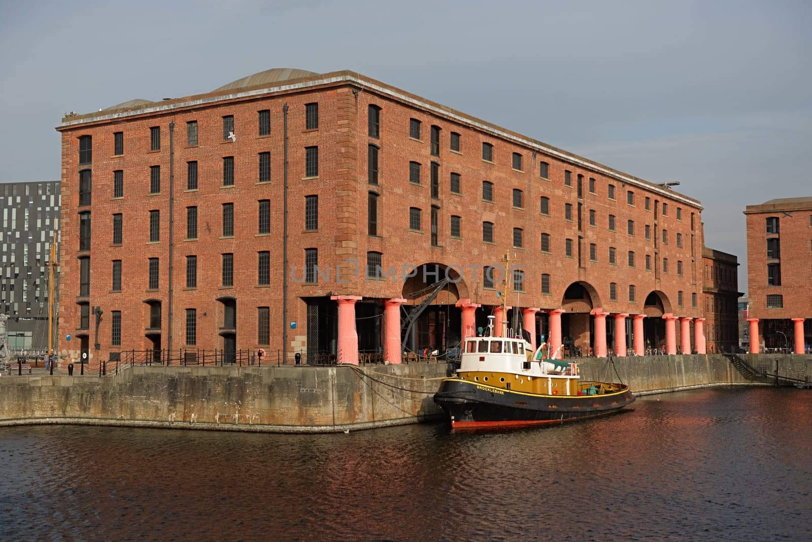 Liverpool, United Kingdom, 2nd February, 2020: Old brocklebank boat moored outside royal albert dock buildings on a sunny spring day, calm water.