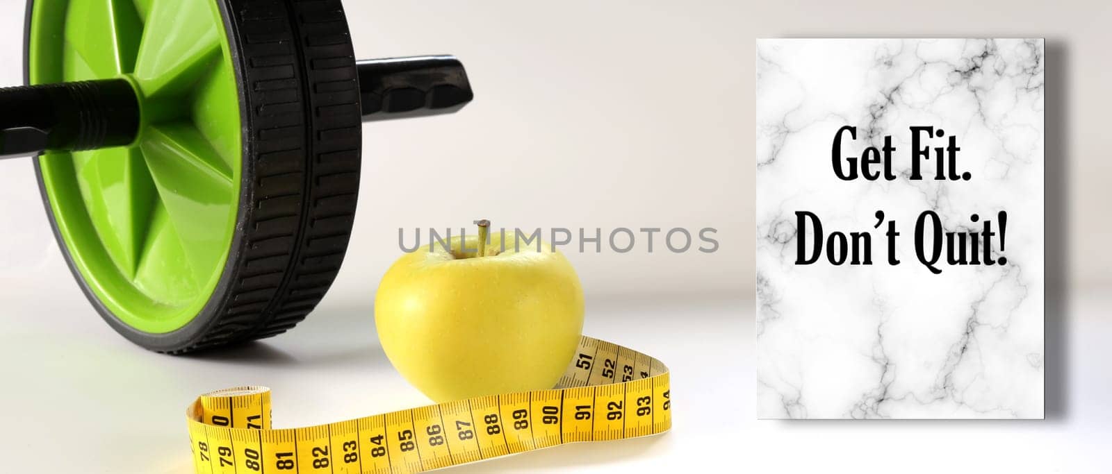 Healthy lifestyle motivational quote. Diet fitness and Healthy life Concept. Motivational Quote text Get Fit. Don't Quit. Apple, measure tape, sport home gym equipment ab roller for diet slimming