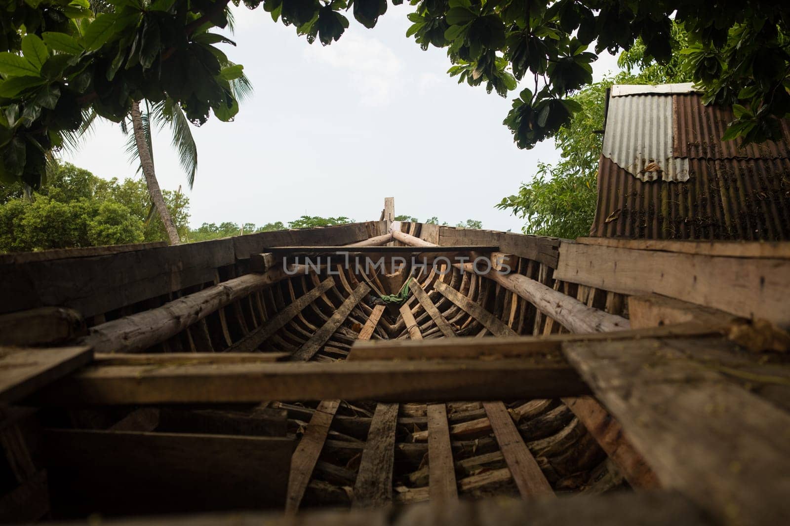 An old fishing boat is being repaired in the harbor by several workers.