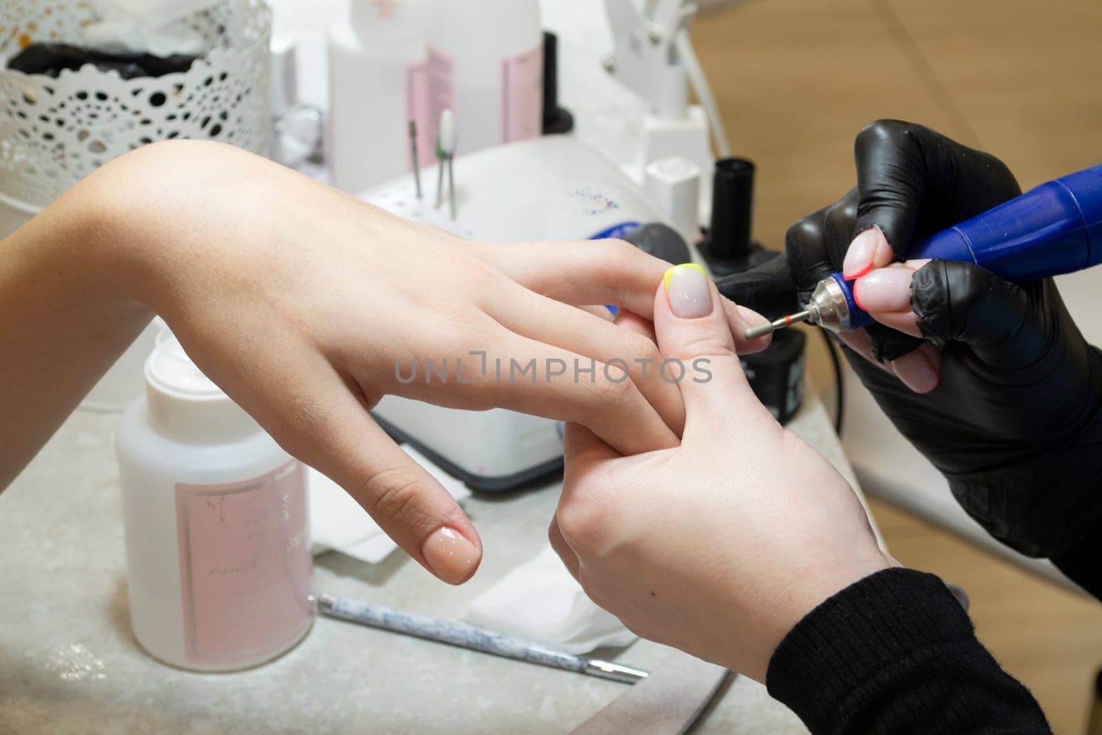 Nails polish procedure. Professional hardware manicure using an electric machine to remove nail polish hands during manicure. Top view