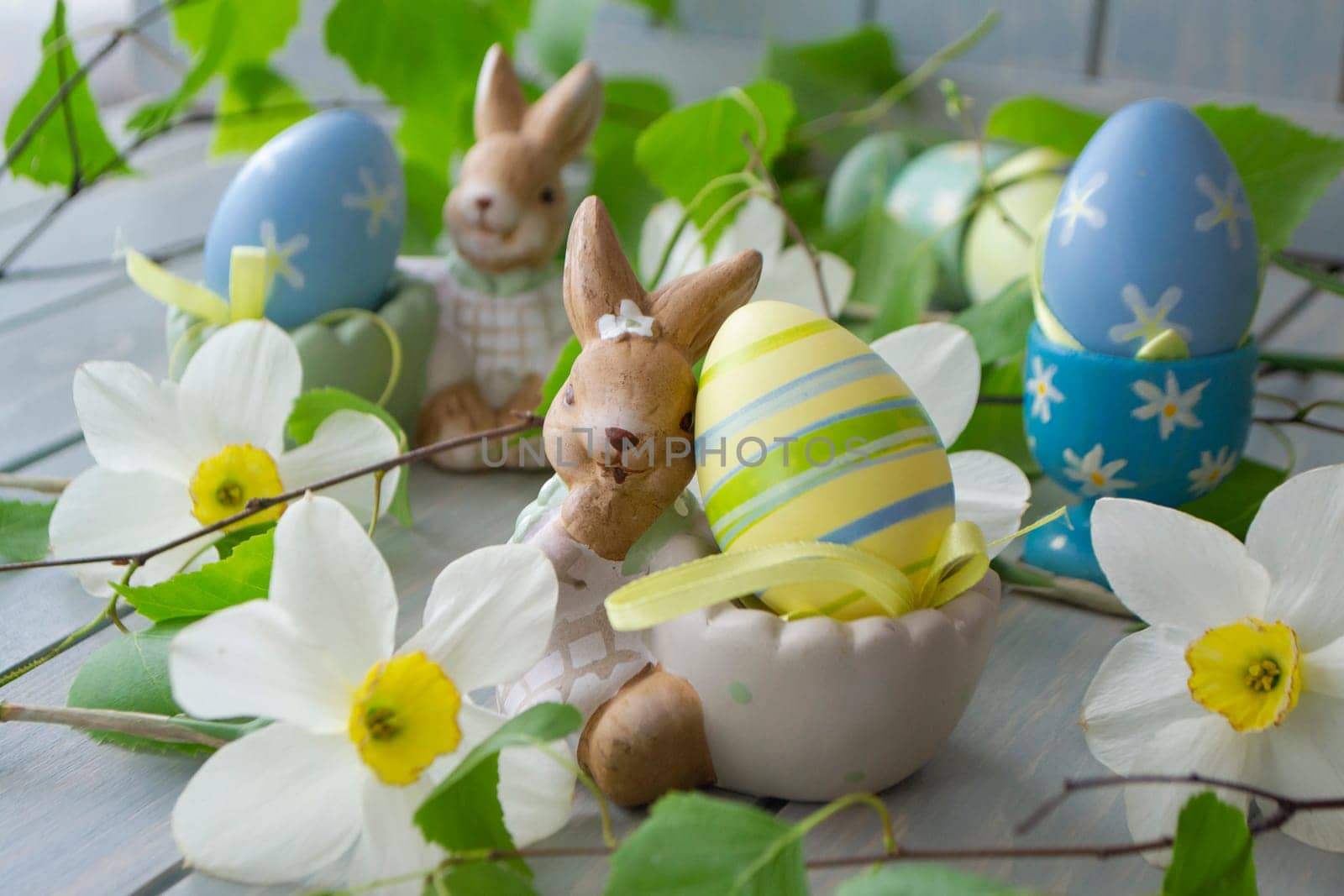 colorful easter eggs and spring flowers on holiday table close up