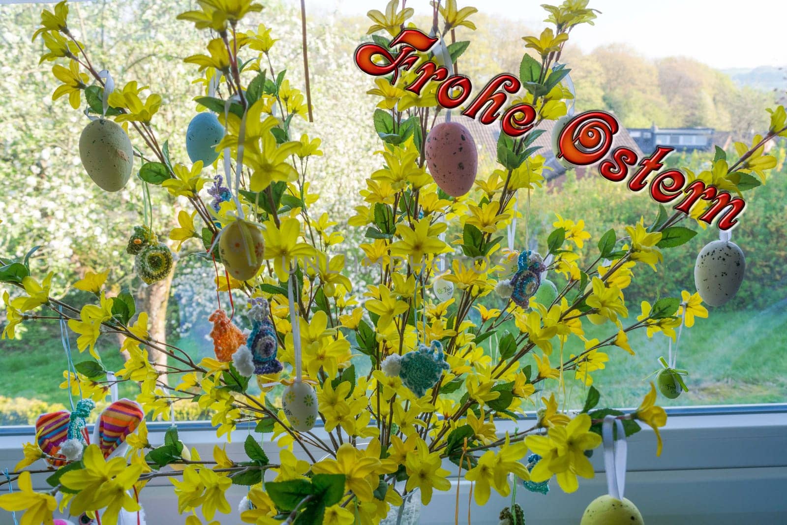 .Colored Easter eggs standing on a forsythia bush in a vase in front of a window. Blur background