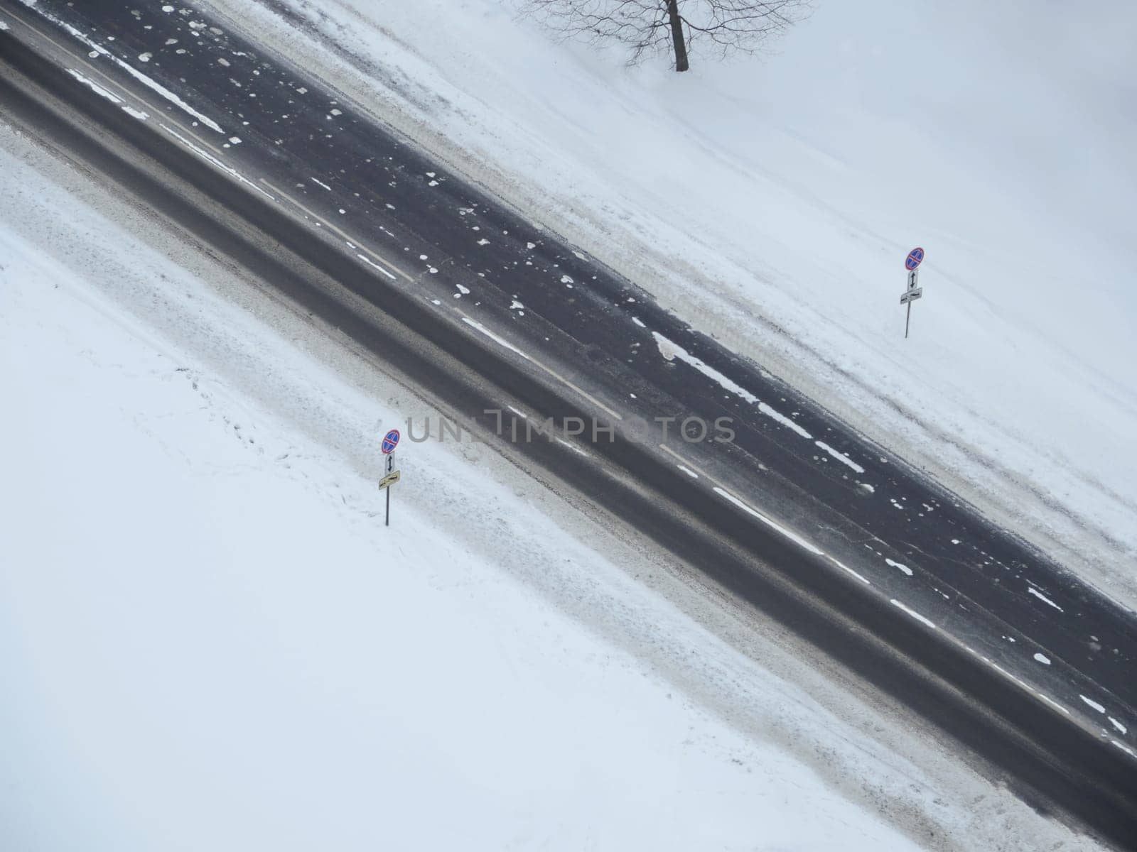 winter road is empty among white snow diagonally from above