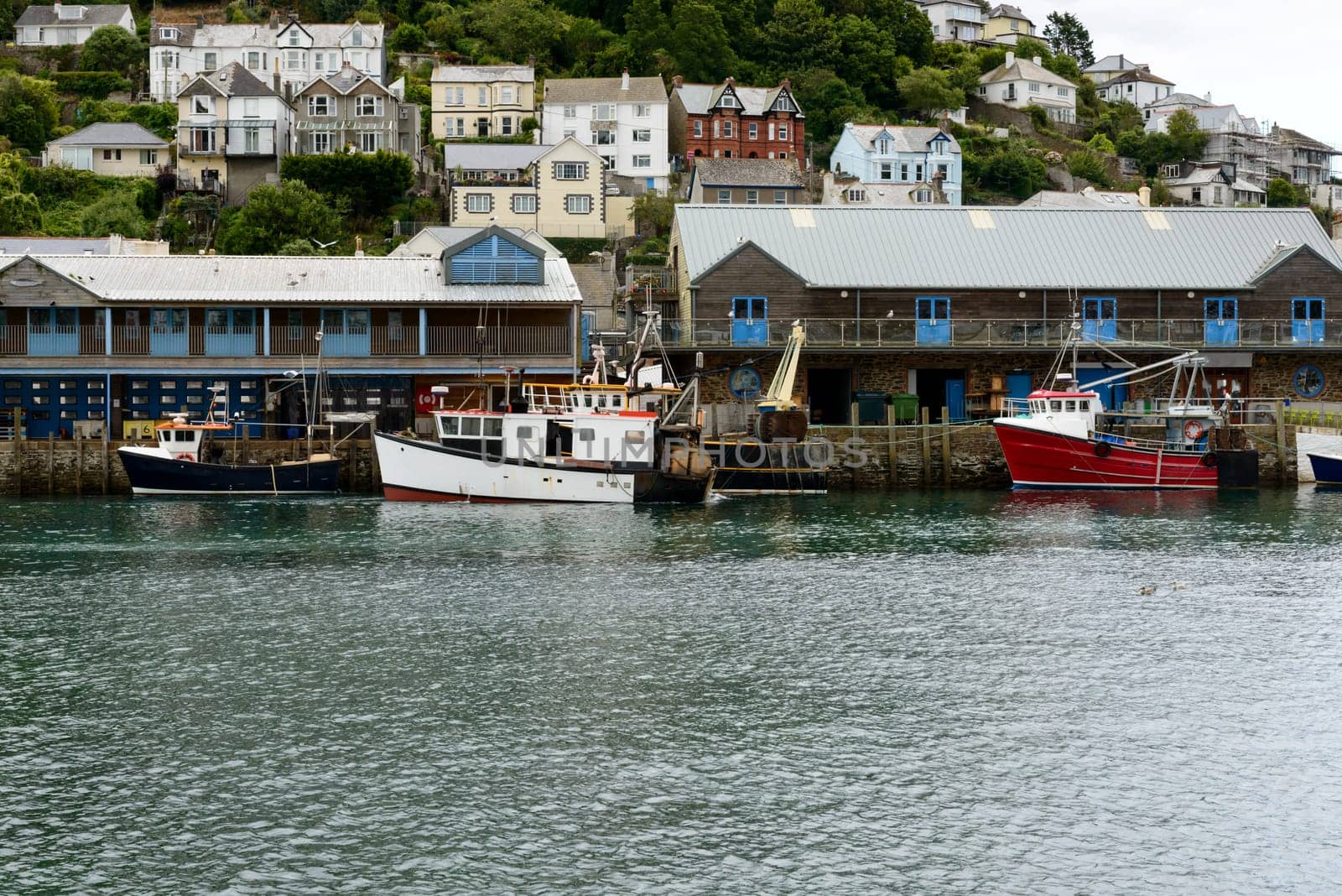 view of old fishboats moored on the embankment of  river in small touristic village on Cornwall southern coast .