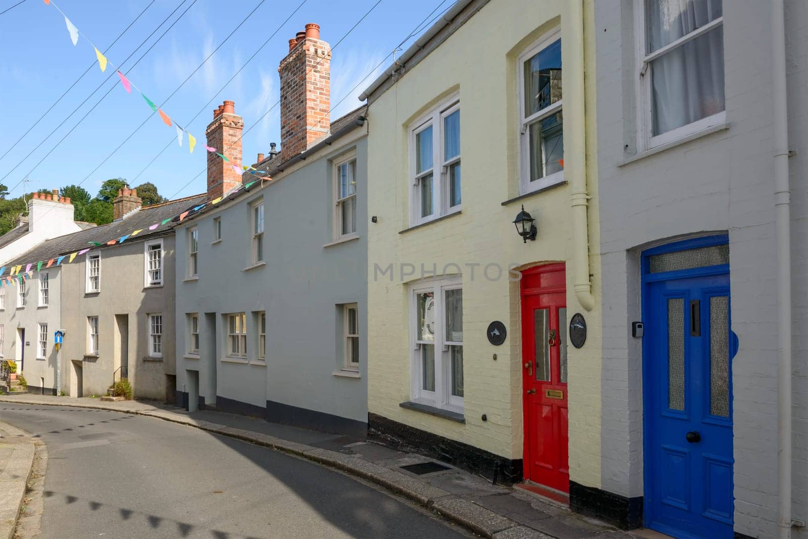 view of bending street with old houses in the village on southern coast of Cornwall.
