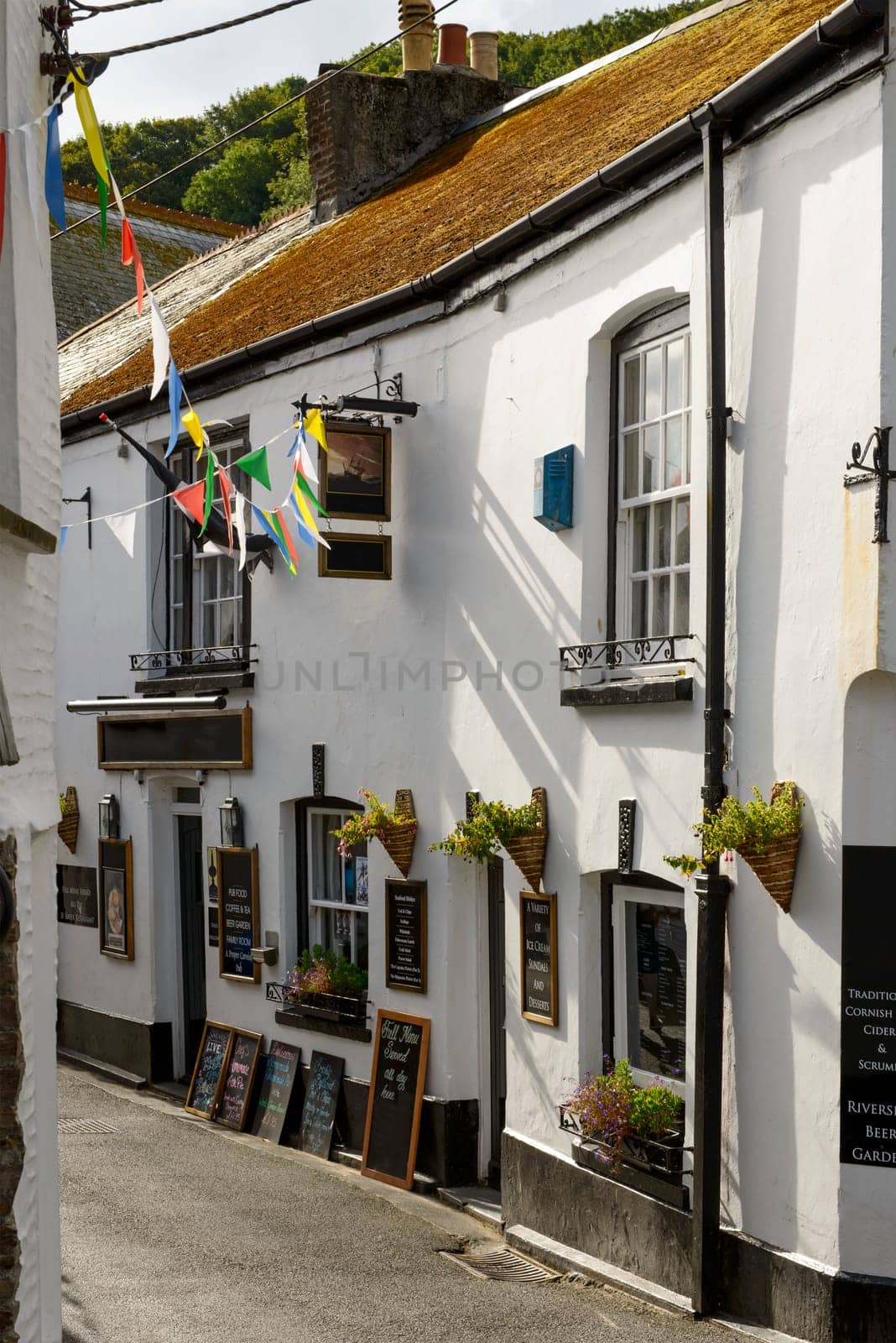view of  old house with a pub inside, shot in a street of the touristic village on southern coast of Cornwall.