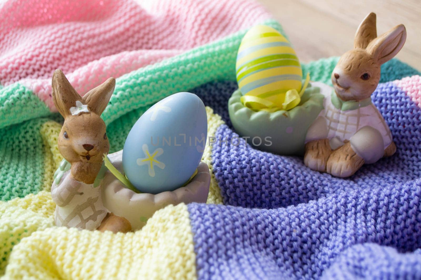 beautiful Easter eggs and bunny on colorful knitted background