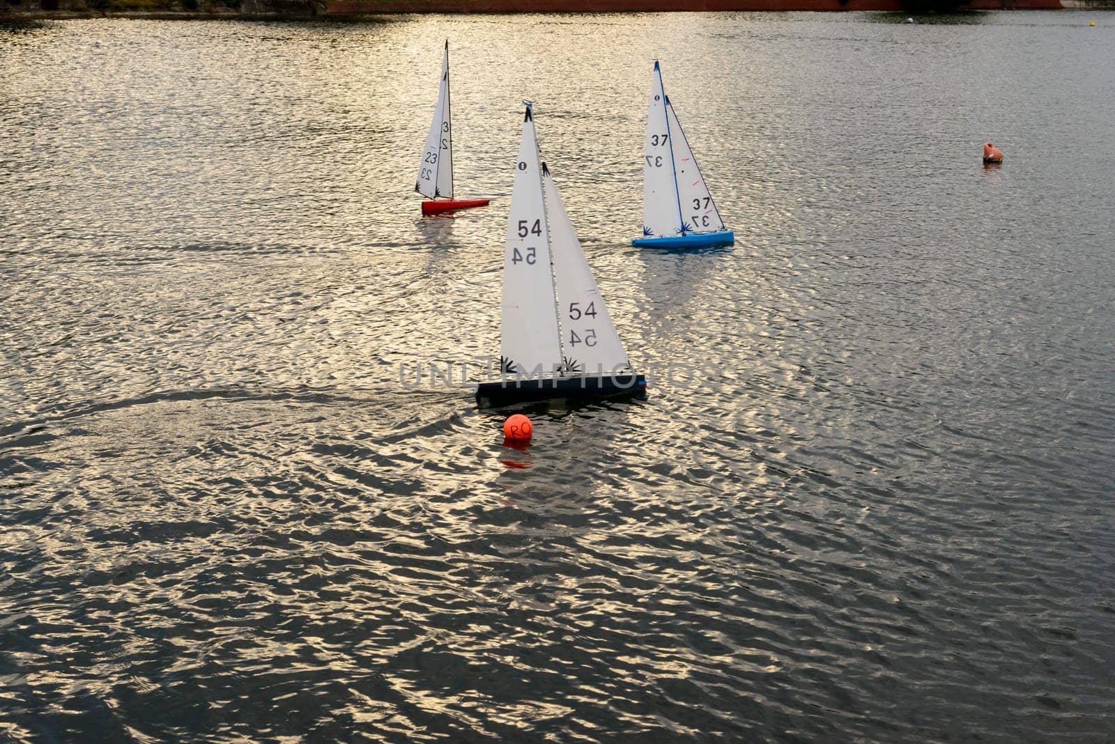miniature sail boats racing in sea pond at touristic sea village .